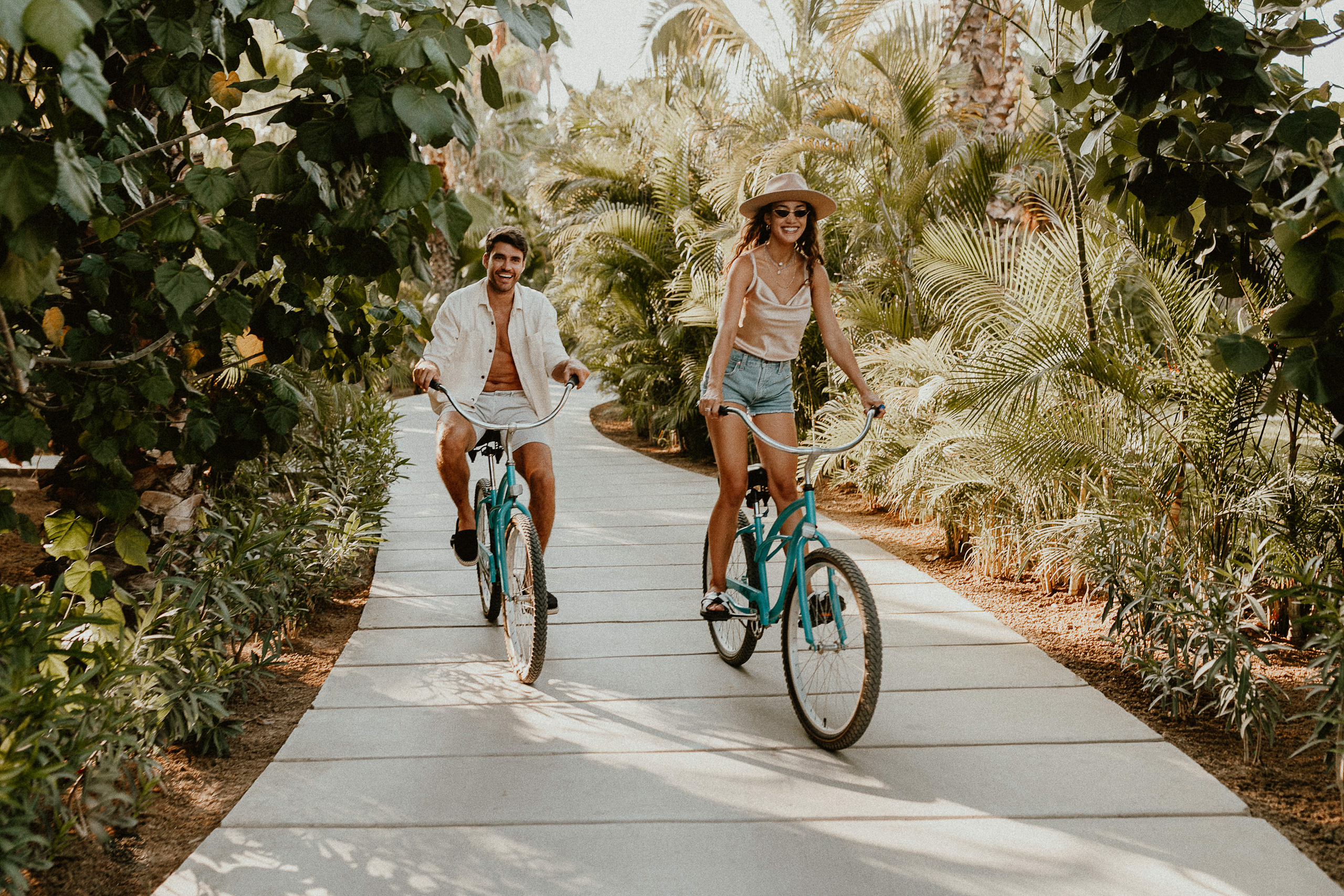 Huéspedes recorren en bicicleta los senderos de Acre Resort Los Cabos rodeados de palmeras