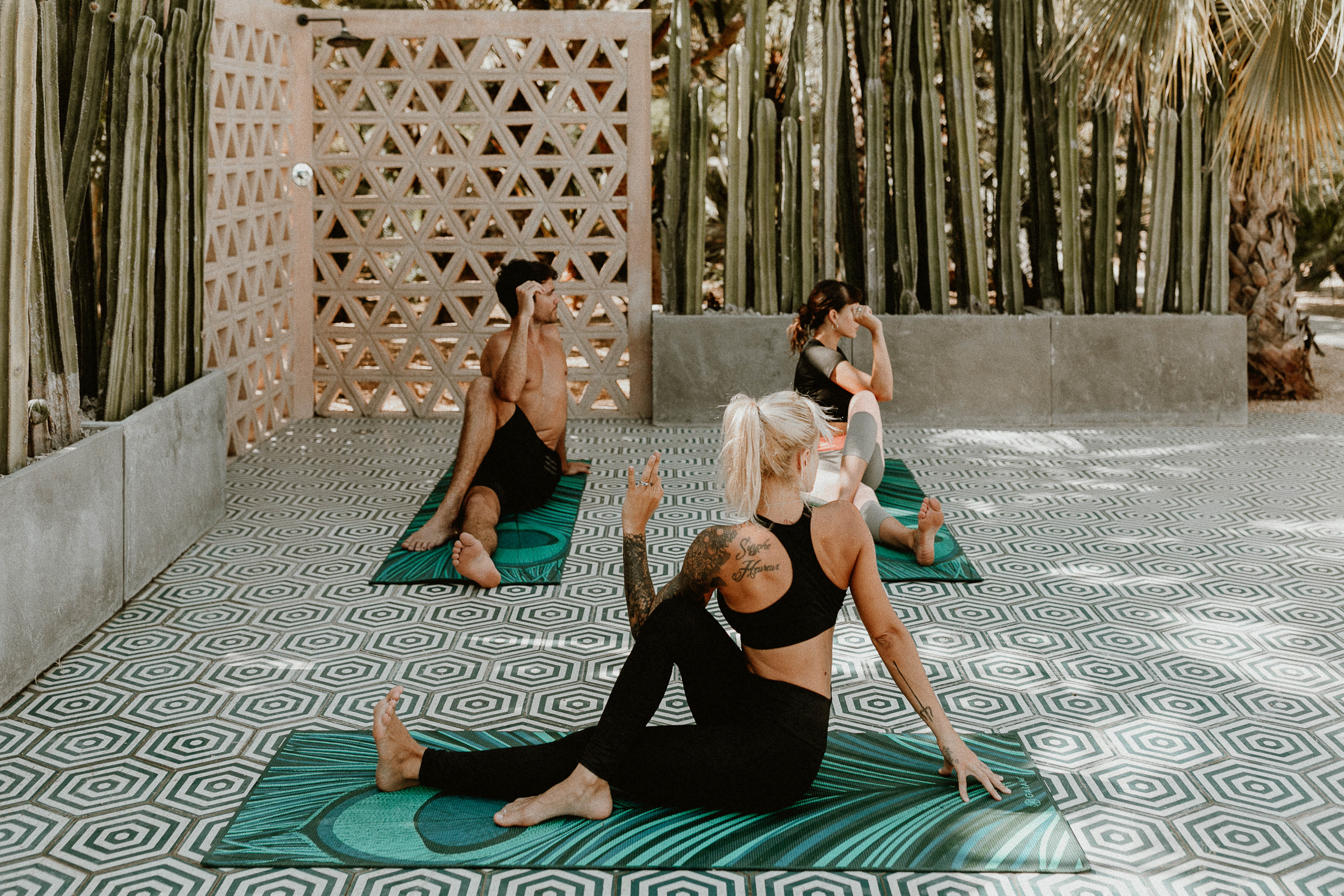 Sesión de yoga al aire libre en Acre Resort Los Cabos rodeada de cactus y vegetación tropical