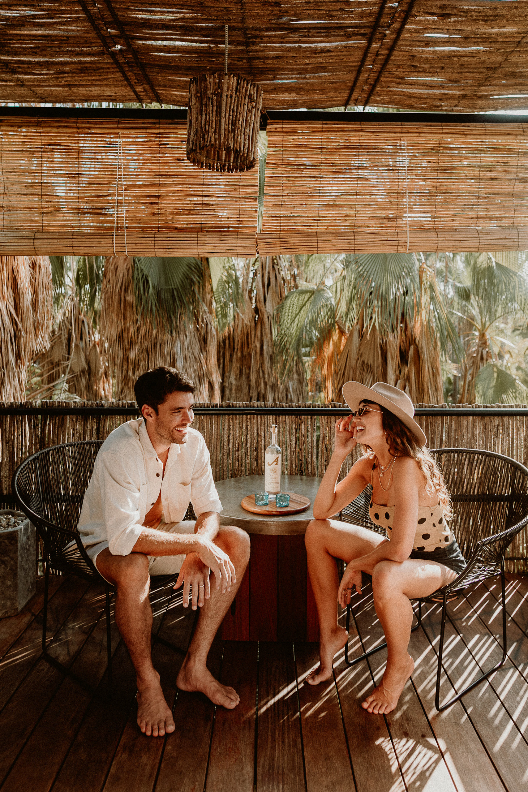 Huéspedes conversan en una terraza de Acre Resort Los Cabos rodeada de vegetación tropical