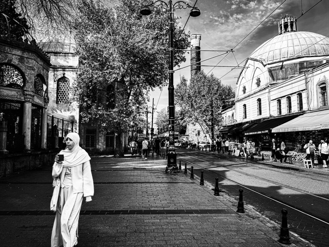 Mujer caminando por una calle histórica de Estambul con cúpula de mezquita al fondo
