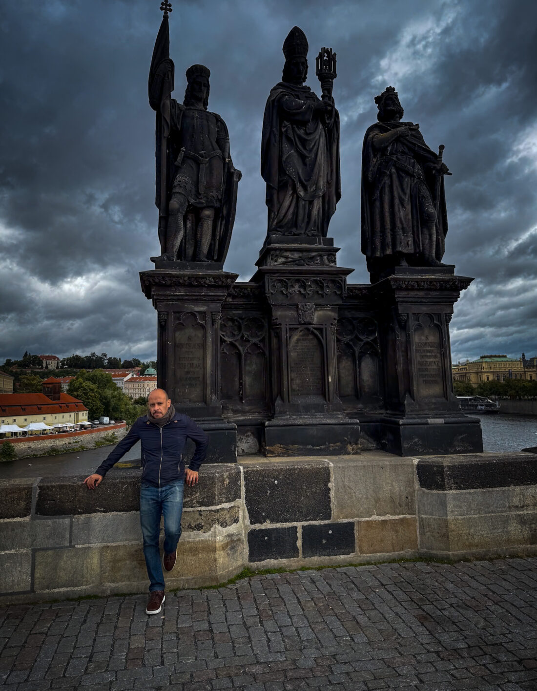 Estatuas barrocas del Puente de Carlos en Praga con cielo dramático sobre el río Moldava