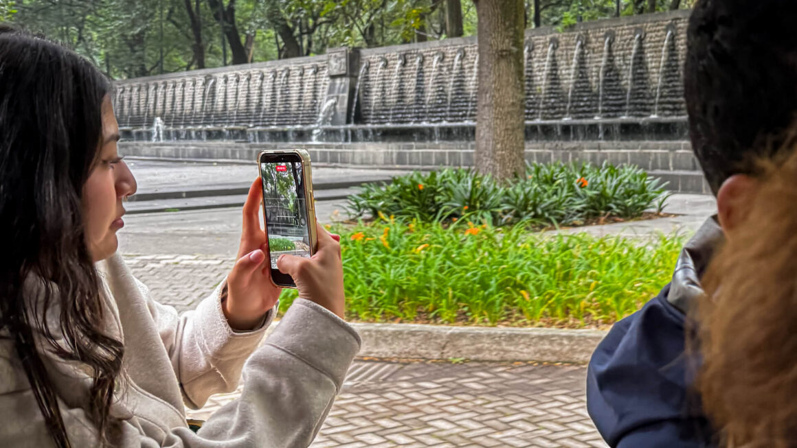 Visitante utilizando la app Bosque de Chapultepec durante un recorrido por el bosque en Ciudad de México.