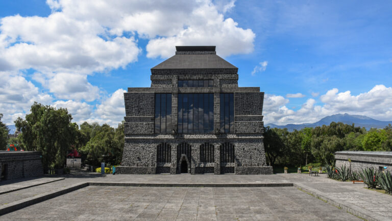 Vista frontal del Museo Anahuacalli bajo un cielo azul con nubes