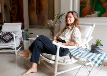 Evgenia sentada en su estudio junto a sus pinturas y espacio de trabajo