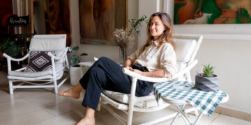Evgenia sentada en su estudio junto a sus pinturas y espacio de trabajo