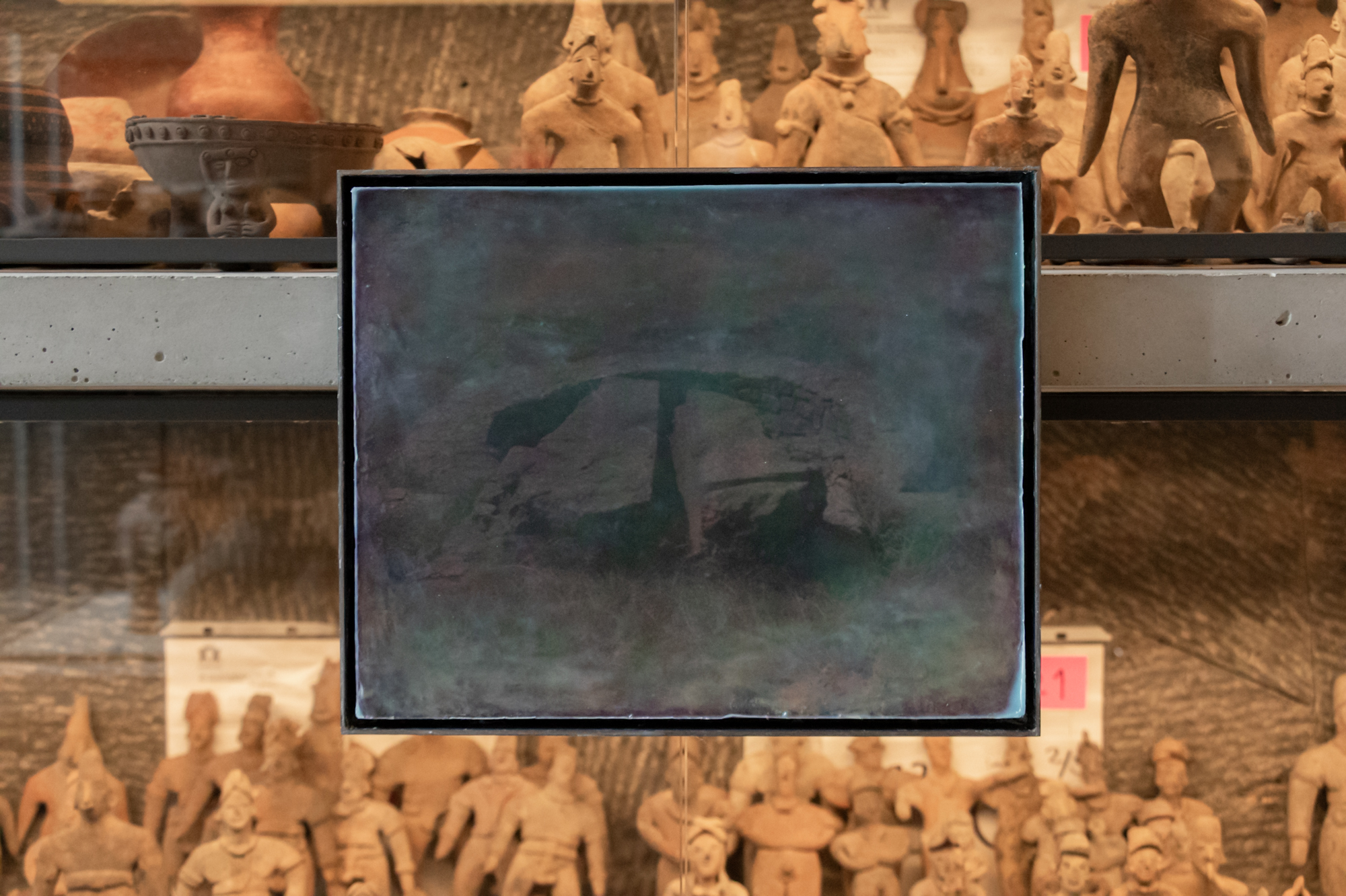 Obra de Silvestre Borgatello con un paisaje rocoso, instalada frente a vitrinas con figuras arqueológicas del Museo Anahuacalli.